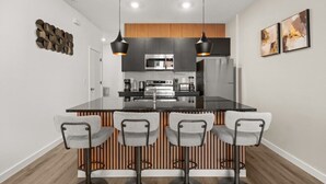 A modern kitchen with a central island, bar stools, and pendant lighting. - Last Minute Disney Getaway! Modern Townhome. Book Now! #158993 (Orlando)