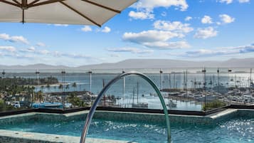 Una piscina con vistas a un puerto deportivo y montañas al fondo.