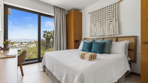 A modern bedroom with a large bed, a desk, and a view of the city. - Alik (La Cruz de Huanacaxtle)