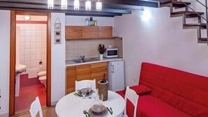 Een ruimtelijk ingerichte leefruimte met een keuken, een eethoek en een rode bank.