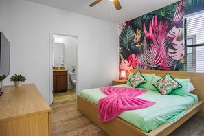 Un dormitorio con cama, mesita de noche, escritorio y una planta en maceta.