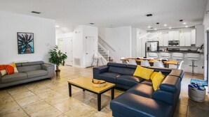 A modern living room with a sofa, a coffee table, and a dining area with a table and chairs. - Last Minute Disney Getaway! Private Pool, Game Room & Themed Bedrooms. Book Now! #162951 (Orlando)