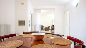 Een eetgedeelte met een ronde tafel, geweven placemats en houten stoelen.