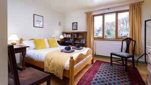 Una camera da letto con un letto di legno, una libreria, una sedia e una finestra con tende.