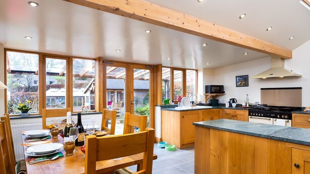 Una cucina moderna con mobili in legno, un'isola centrale e ampie finestre.