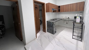 A compact kitchen with wooden cabinets, a marble countertop, and a built-in gas stove. - Departamento Residencial San Juan Bosco  (Guadalajara)