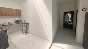 A modern kitchen with a marble countertop, wooden cabinets, and a built-in microwave. - Departamento Residencial San Juan Bosco  (Guadalajara)