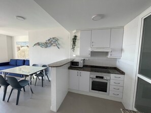 Eine moderne Küche mit weißen Schränken, einer Mikrowelle, einem Backofen und einem Essbereich mit Tisch und Stühlen.