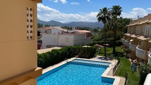 A swimming pool with a clear view of the surrounding buildings and mountains in the background. - Balcony overlooking the Mediterranean Sea, wonderful natural fine sandy beach (Oliva)