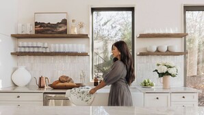 A modern kitchen with white cabinetry, a marble countertop, and a large window.