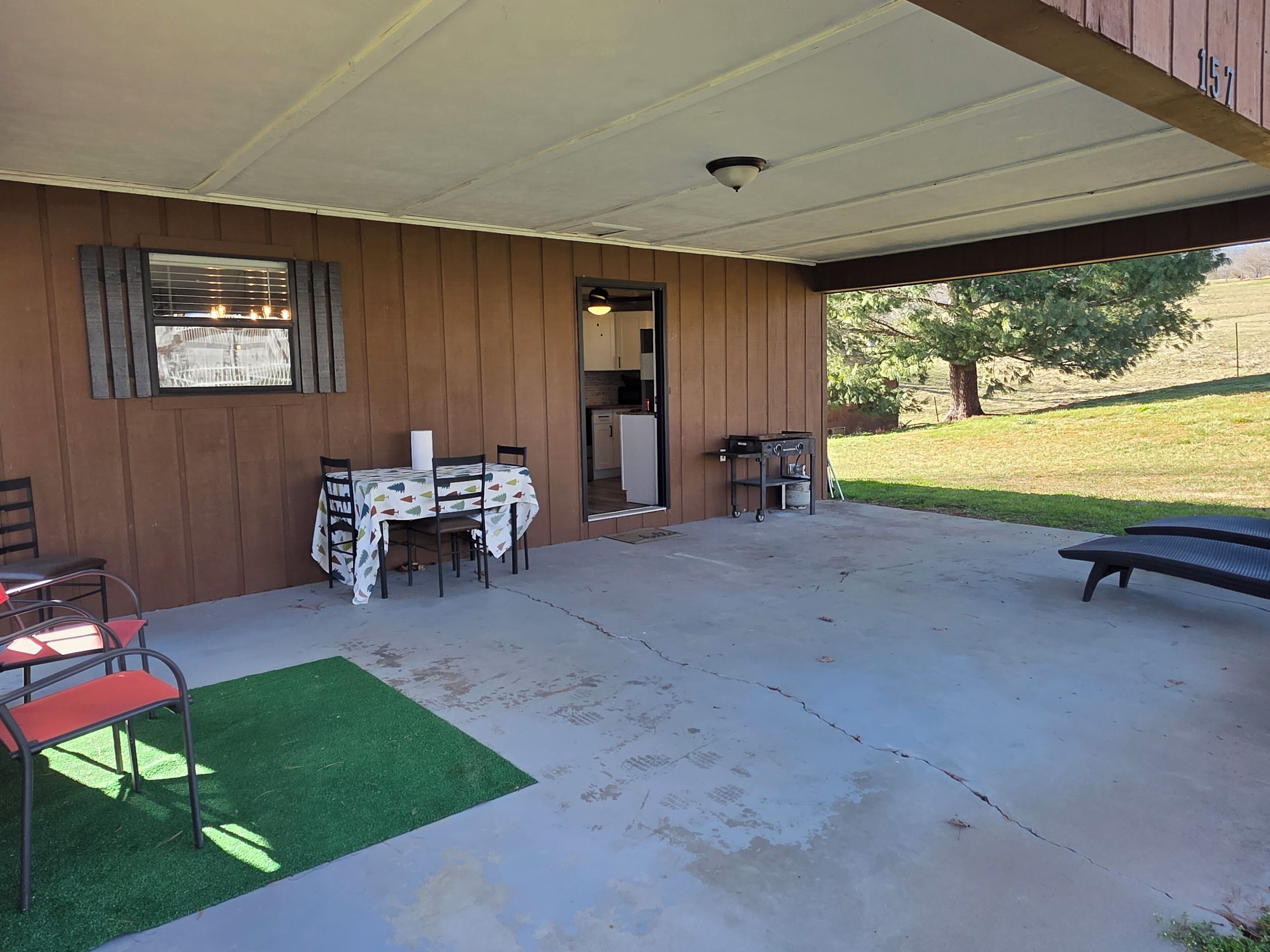 Un patio abrité avec une table et des chaises, un petit barbecue et un banc.