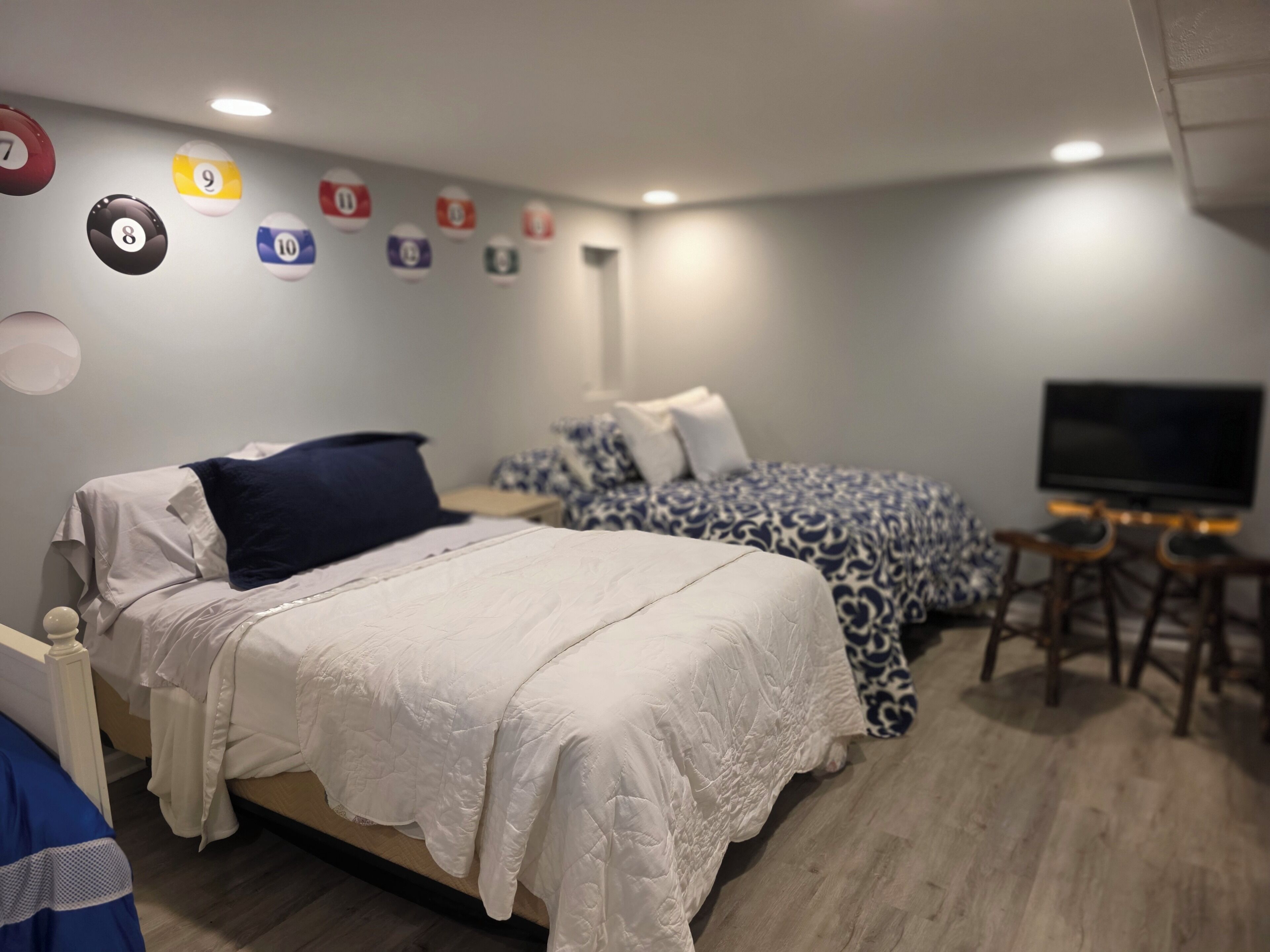 A bedroom with two beds, a TV, and a pool table.