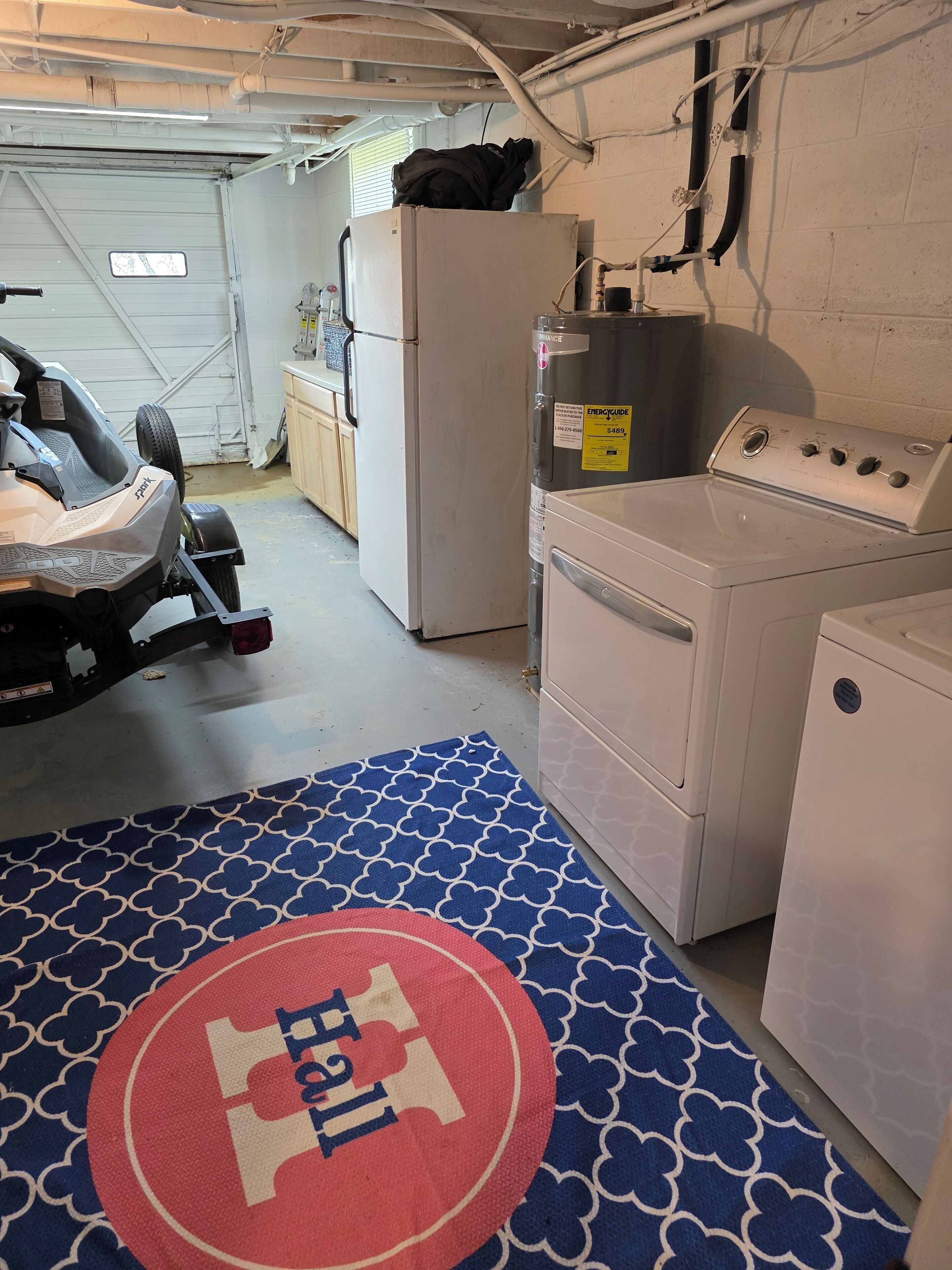 A garage with a vehicle, a refrigerator, a washing machine, and a utility meter.