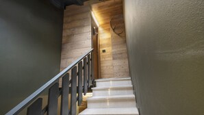 Eine Treppe mit Holzstufen und einem Metallgeländer, die zu einem Raum mit einer Holzwand und einer Leuchte führt.