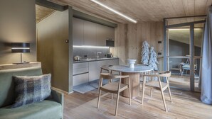 Eine moderne Küche mit Holzausstattung, einem runden Esstisch mit Stühlen und einer Couch mit Lampe.