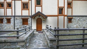 A stone building with a central wooden door, stone walls, and wooden window frames. - AlpinWood - Two Bedroom Apartment, Sleeps 5 (Temù)
