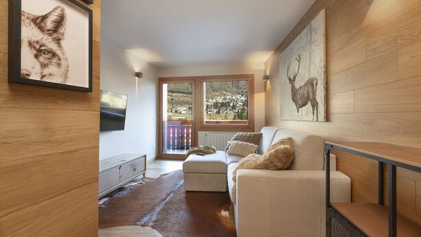 A modern living room with a sofa, a TV, and artwork on the walls. - AlpinWood - Two Bedroom Apartment, Sleeps 5 (Temù)
