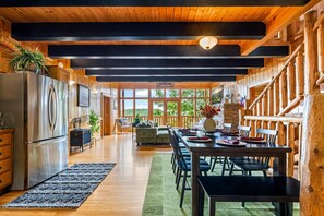 A spacious kitchen with a large refrigerator, wooden ceiling, and a dining area with a table set for four. - Mistwood Manor | Hot Tub • Sauna • Game Room (Sevierville)