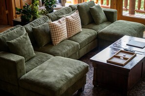 A sectional sofa with a woven texture, a coffee table with a tray, and a potted plant. - Mistwood Manor | Hot Tub • Sauna • Game Room (Sevierville)
