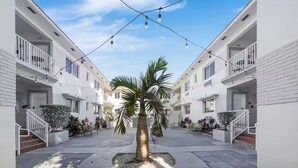 A courtyard with a palm tree, white buildings, and string lights. - The Donovan Hotel (Miami Beach)