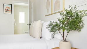 A bedroom with a bed, white pillows, a potted plant, and artwork on the wall. - The Donovan Hotel (Miami Beach)