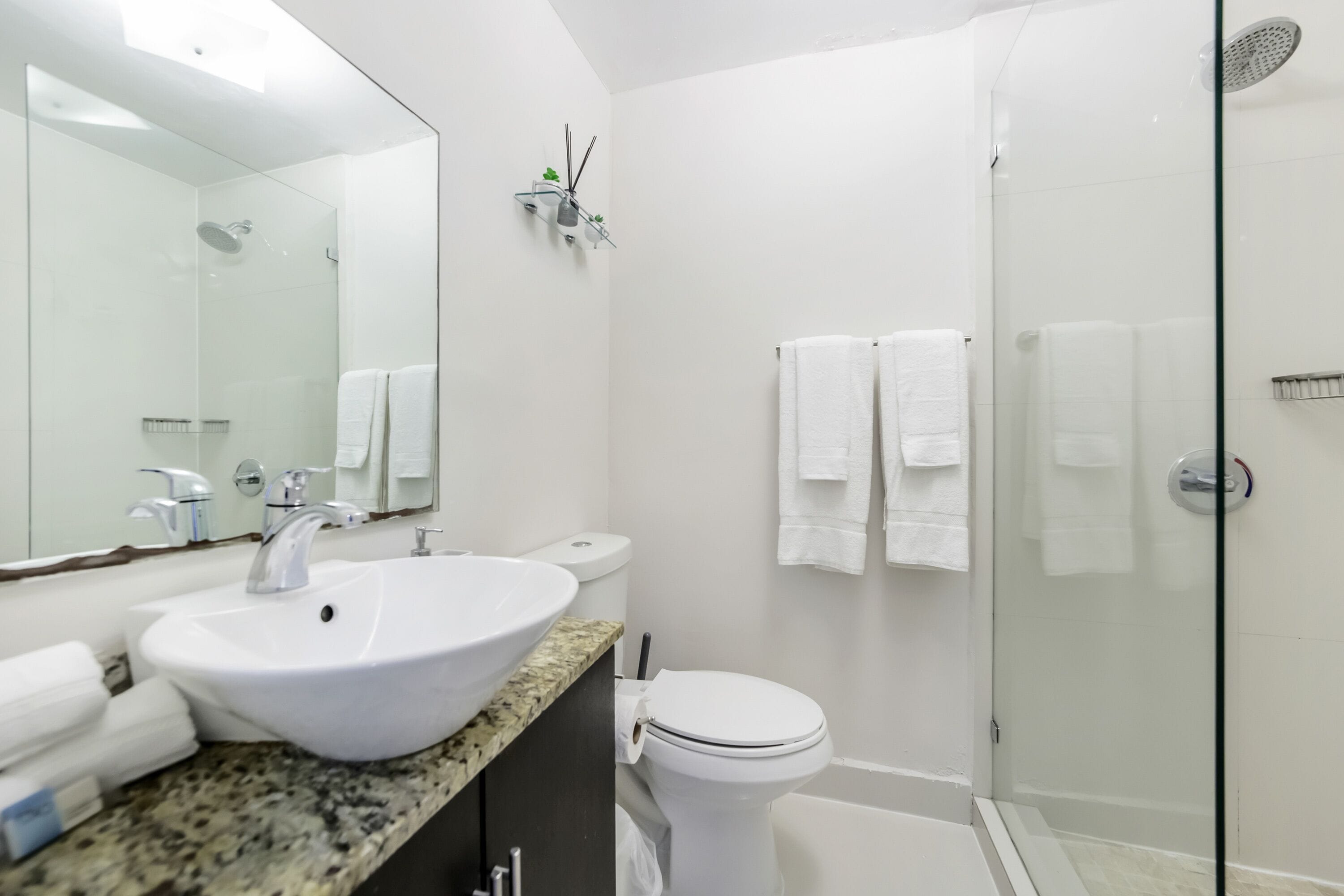 Een moderne badkamer met een wit wastafelmeubel, toilet en douchecabine.
