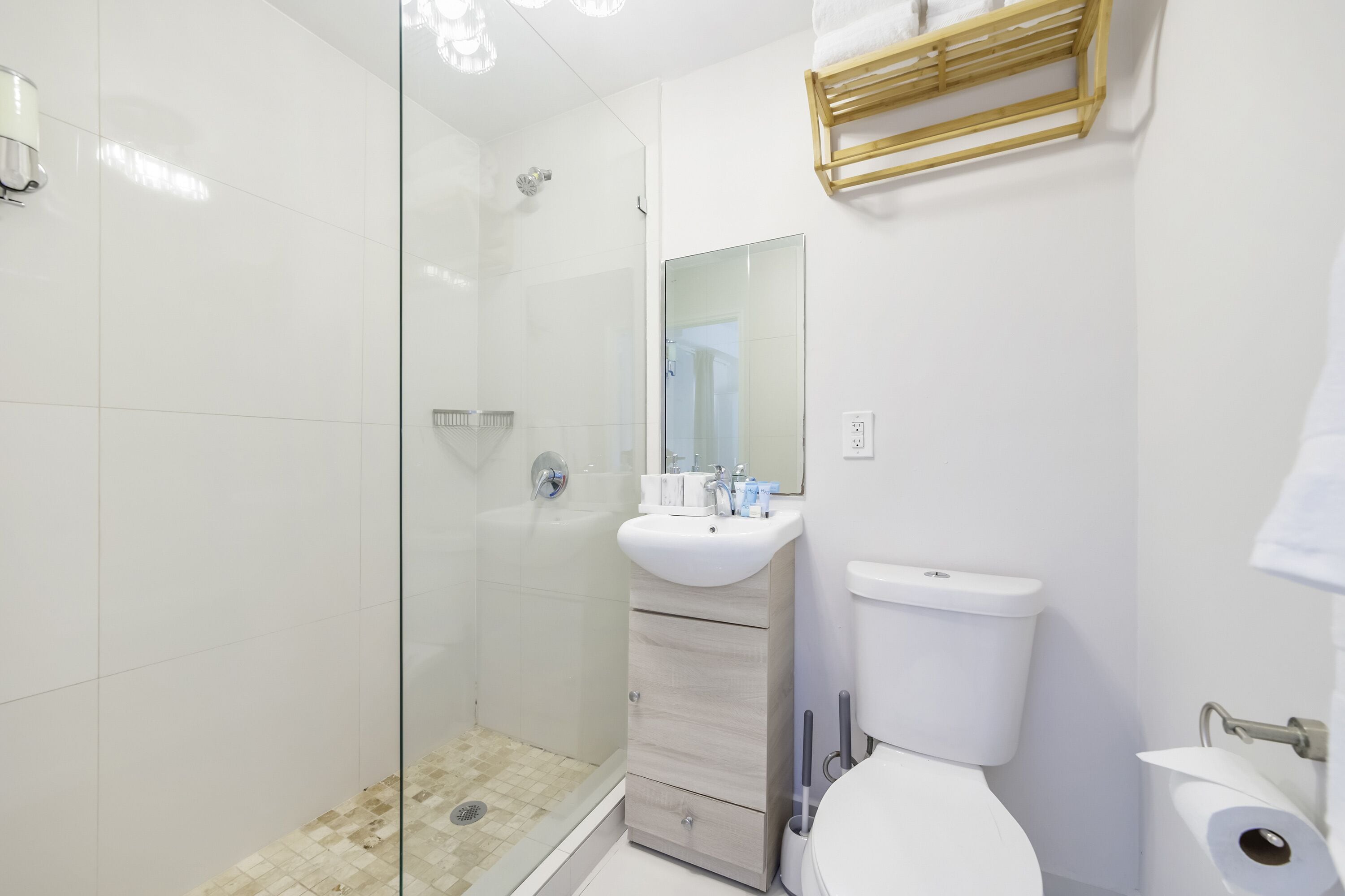 A modern bathroom with a glass shower enclosure, a sink with a mirror, and a toilet.