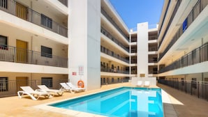 A multi-level hotel with a central swimming pool, balconies, and lounge chairs. - ‘Ria Formosa Pool Heaven’ Apartment with Shared Pool, Wi-Fi, and Air Conditioning (Olhão)
