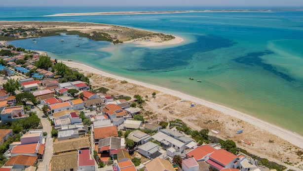 An aerial view of a coastal town with houses, a beach, and clear blue waters. - ‘Ria Formosa Pool Heaven’ Apartment with Shared Pool, Wi-Fi, and Air Conditioning (Olhão)