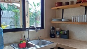 Una cucina compatta con lavandino, finestra e ripiano con stoviglie e utensili.