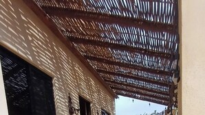 A covered patio area with a table and chairs, potted plants, and a view of a neighboring building. - Charming Private Cottage in Tranquil San Pedrito, El Pescadero- 2 Blocks to Surf (El Pescadero)
