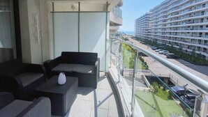 A balcony with outdoor furniture, a view of a multi-story building, and a parking area. - Platinium house (Sâncraiu de Mureș)