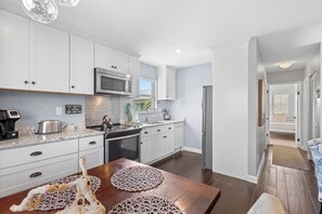 A modern kitchen with white cabinets, stainless steel appliances, and a wooden dining table with decorative placemats.
