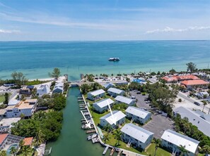 An aerial view of a coastal residential area with houses, a marina, and a clear view of the ocean.