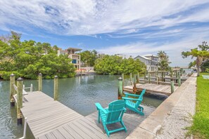 A wooden dock with chairs, a calm water body, and greenery.