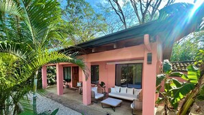 Un bâtiment rose doté d’un patio couvert, d’un canapé et d’une table.