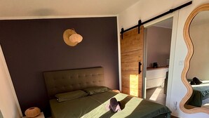 Un dormitorio con una cama grande, una mesita de noche, un espejo y una puerta de madera.