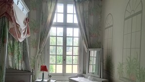 A bedroom with a bed, a desk, a radiator, a chair, and a window with curtains. - Manoir de Villers (Saint-Pierre-de-Manneville)