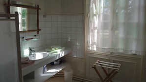 A bathroom with a white sink, mirror, and a window with sheer curtains. - Manoir de Villers (Saint-Pierre-de-Manneville)