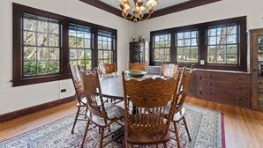 A dining room with a wooden table, chairs, and a chandelier.