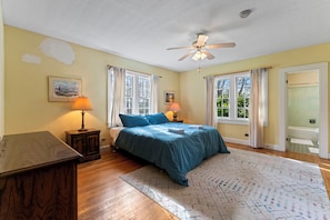 A bedroom with a bed, two bedside lamps, a ceiling fan, and a window with curtains. - Gorgeous 5-bedroom Riverside Estate Lodge in downtown Townsend (Townsend)