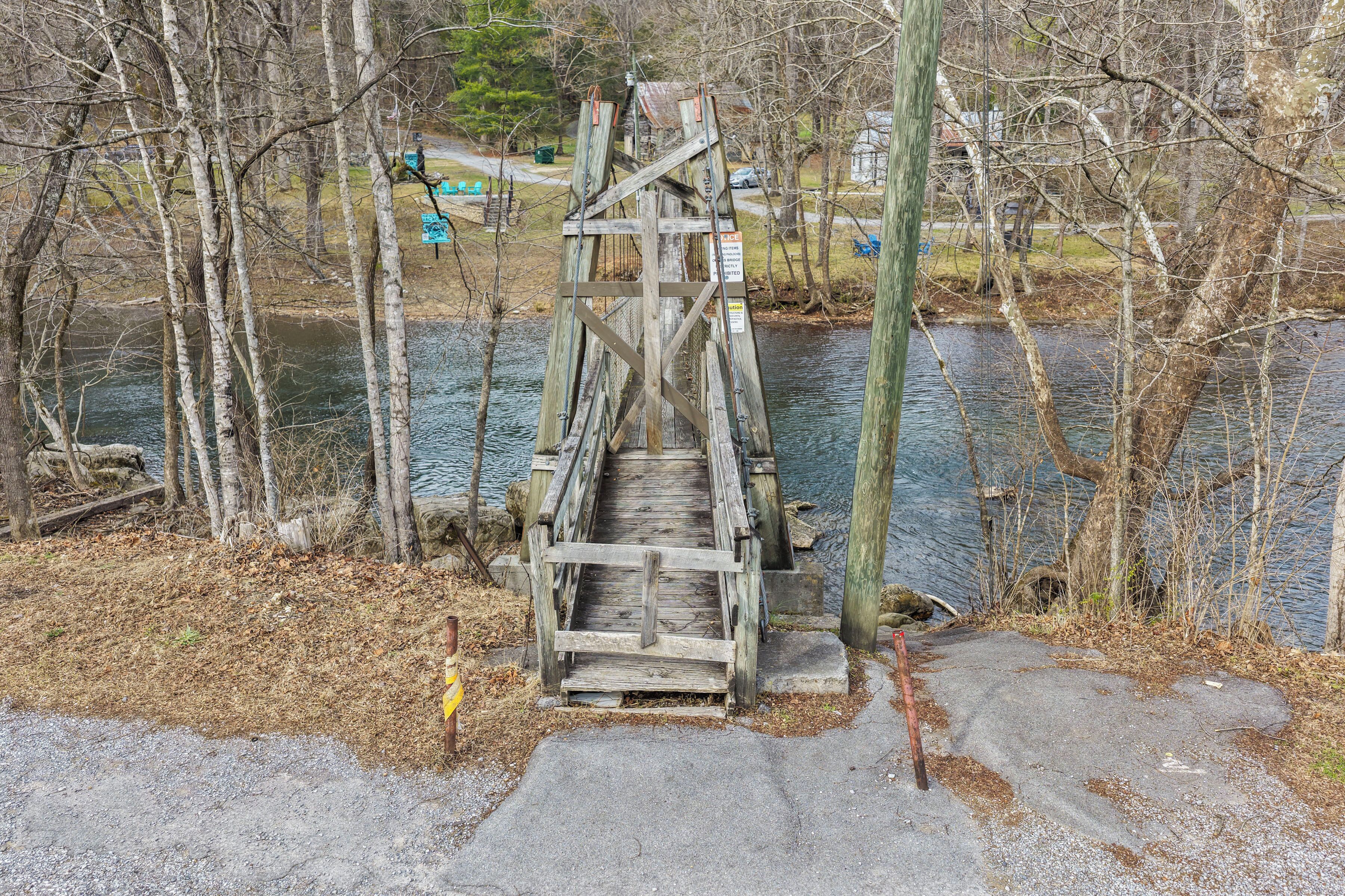 Un puente de madera sobre un río, con un sendero de concreto que lo conecta.