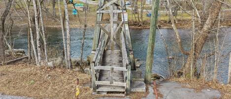 Un puente de madera sobre un río, con un sendero de concreto que lo conecta.