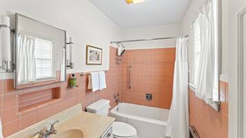 Une salle de bain comprenant une baignoire, des toilettes, un lavabo et un espace douche.