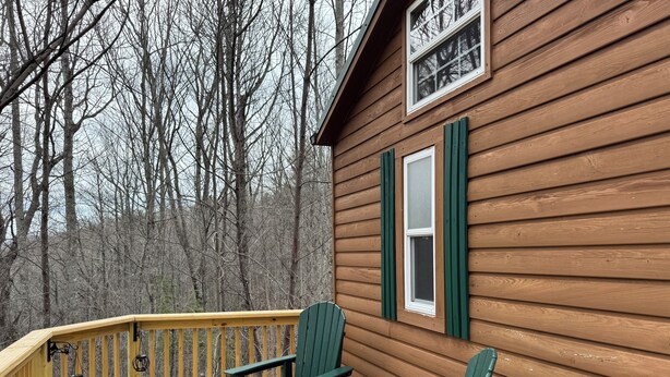 A wooden deck with two green Adirondack chairs and a wooden railing. - Tiny Home II, Pet Friendly, Free Cancellations (Boone)