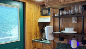 A compact kitchen with wooden cabinets, a microwave, and a countertop with a sink. - Tiny Home II, Pet Friendly, Free Cancellations (Boone)