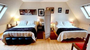 Quarto com duas camas, soalho de madeira e claraboia.