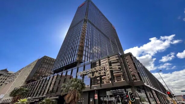 A tall skyscraper with a modern glass facade and a sign reading "Foreshore Place." - Modern Foreshore Apartment | City Views, WiFi & Parking (Cape Town)