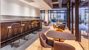 A modern conference room with a bar area, multiple seating arrangements, and large windows offering a view of the cityscape. - Modern Foreshore Apartment | City Views, WiFi & Parking (Cape Town)