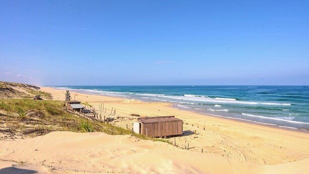 A beach with a small wooden structure and a sandy dune. - Cosy house with garden - near Mimizan beach (Mimizan)